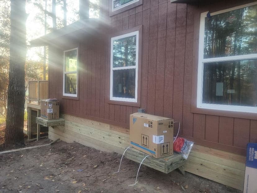 Boxes on wooden platforms beside a newly constructed house in a wooded area.